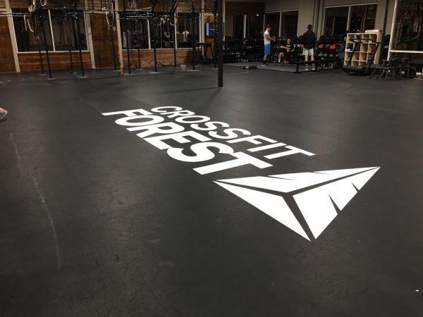 Custom CrossFit Forest logo decal applied on a black gym floor.