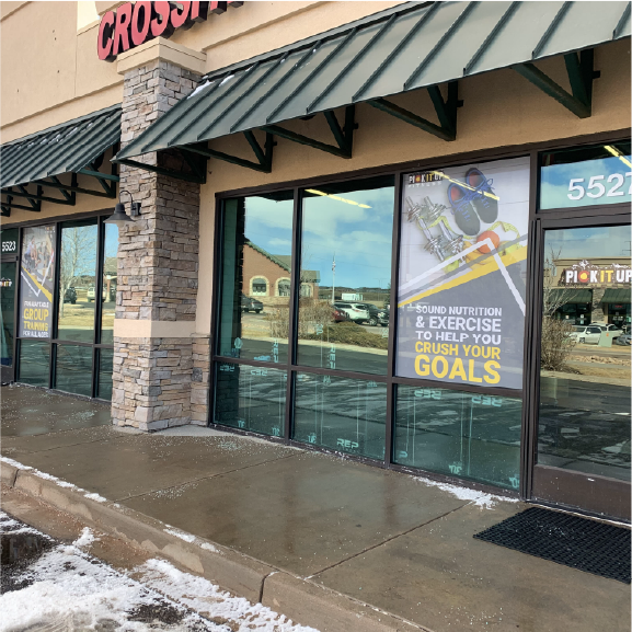 Gym storefront with perforated vinyl promoting nutrition and exercise goals.