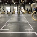 Numbered workout lanes marked on a gym floor with white tape and labeled stations.