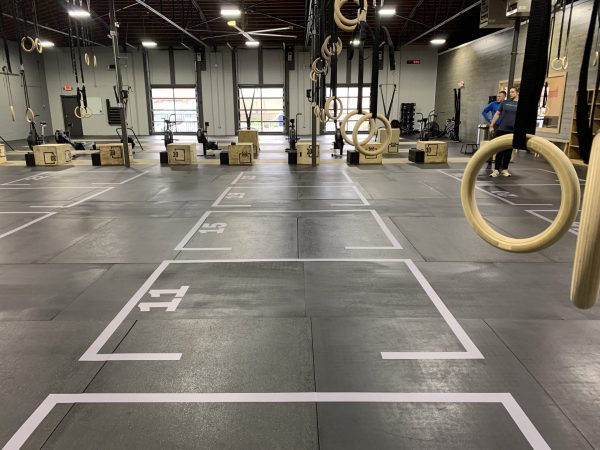 Numbered workout lanes marked on a gym floor with white tape and labeled stations.