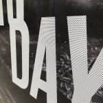 Close-up of perforated window vinyl with bold white text and black background.