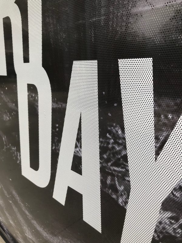 Close-up of perforated window vinyl with bold white text and black background.