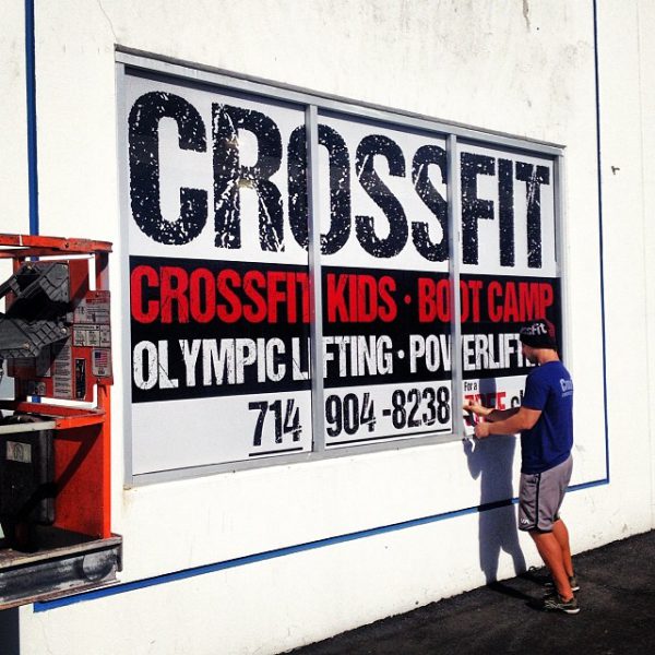 CrossFit window graphic with bold class offerings and contact info.