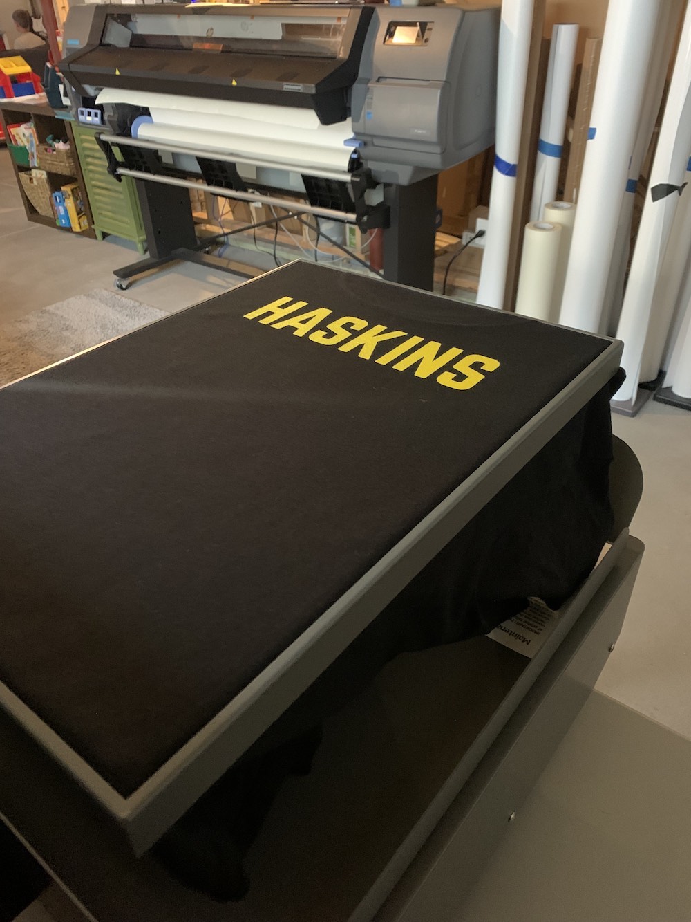 Custom black t-shirt with bold yellow HASKINS text in heat press setup