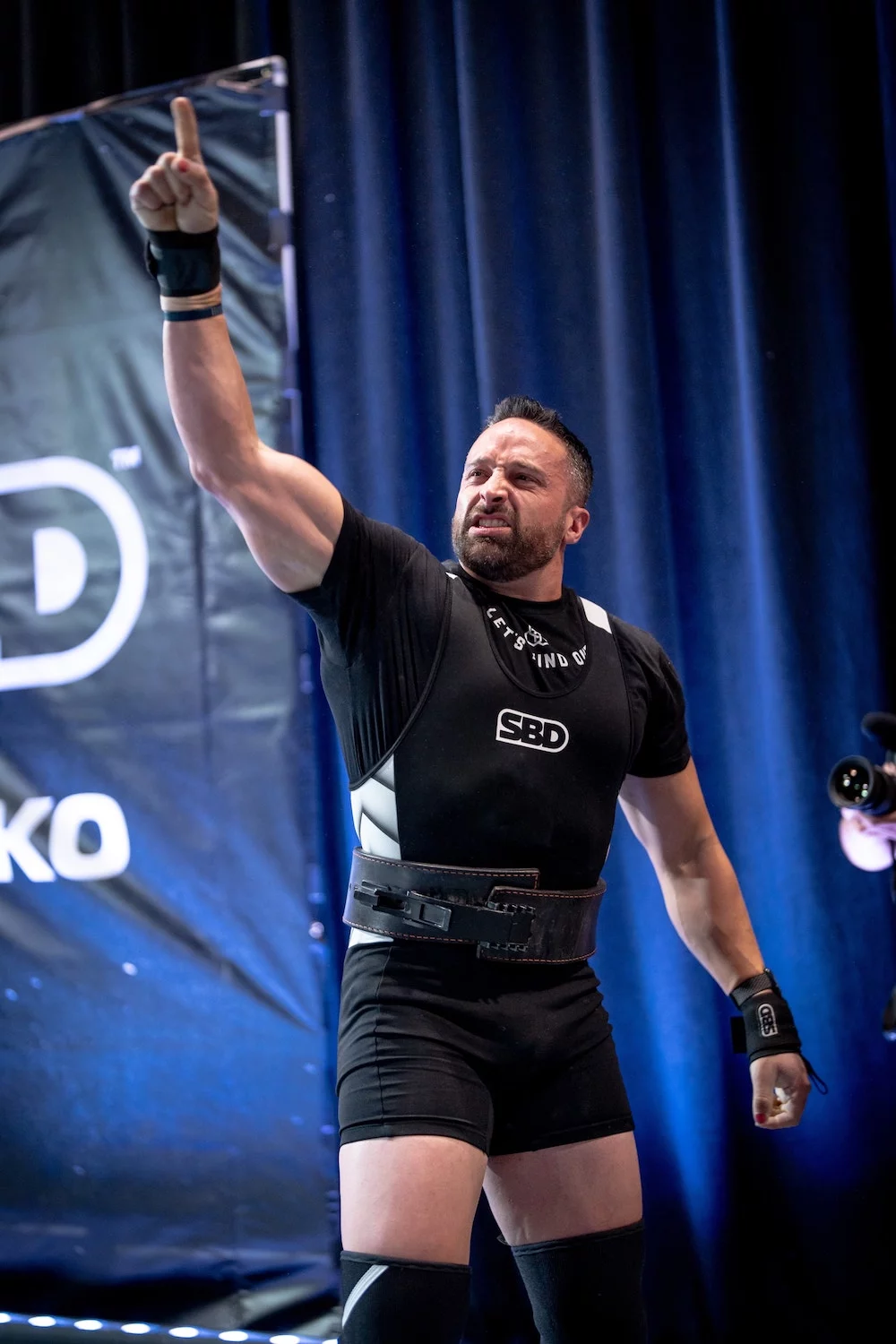 Powerlifter celebrates on stage with raised fist at competition