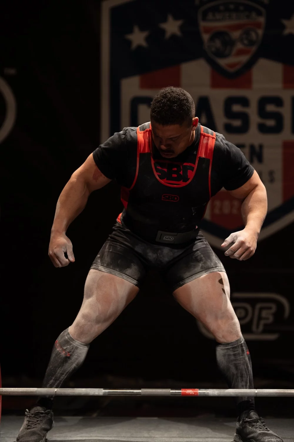 Powerlifting athlete chalks up before a lift at Powerlifting America competition